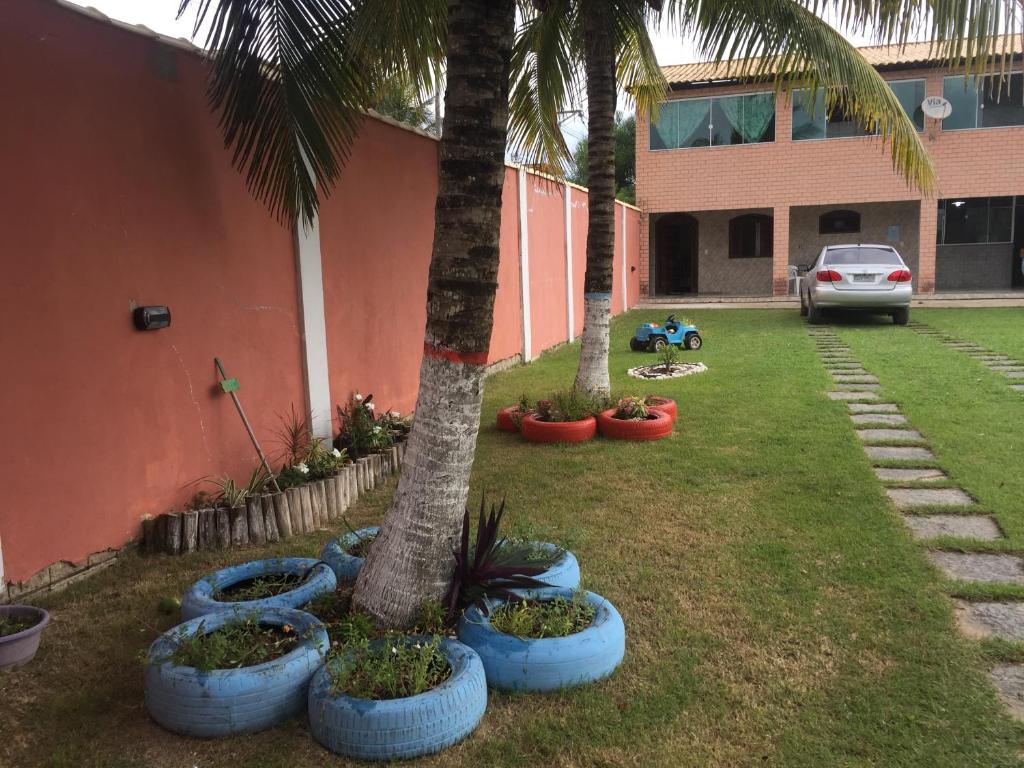 un patio con palmeras y plantas azules junto a un edificio en Nossa Chácara na Praia 3suits,Camp,Pisci,Churrasqueira e estacionamento, en Arraial do Cabo