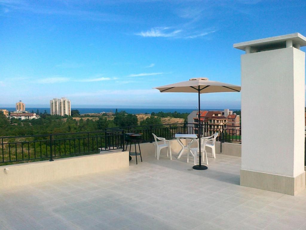 balcón con sombrilla, mesas y sillas en Villa Denta, en Nesebar