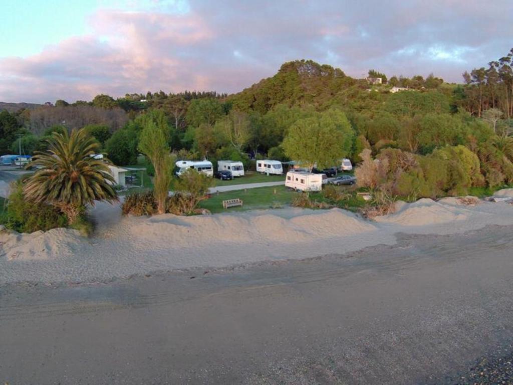 una vista aerea di un campeggio alberato e di una spiaggia di Golden Bay Holiday Park a Onekaka