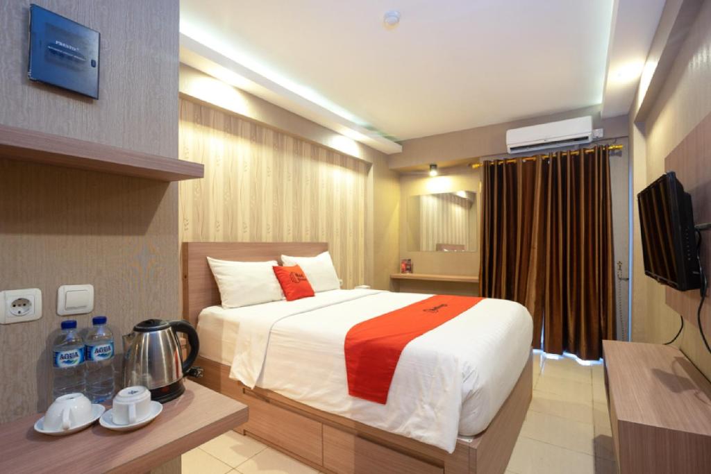 Habitación de hotel con cama y TV en RedDoorz Apartment at Bogor Valley, en Bogor
