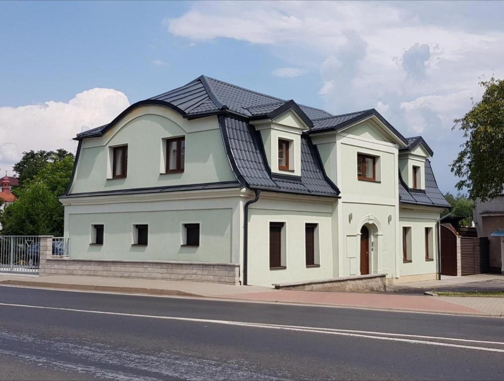 a white house with a black roof on a street at Apartmány Meandry in Mimoň