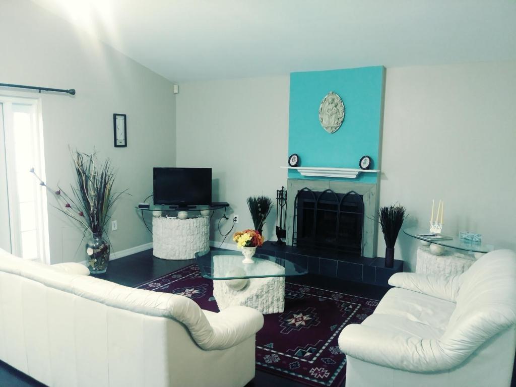 a living room with two white chairs and a fireplace at WelcomeHomeLakeland, FL in Lakeland