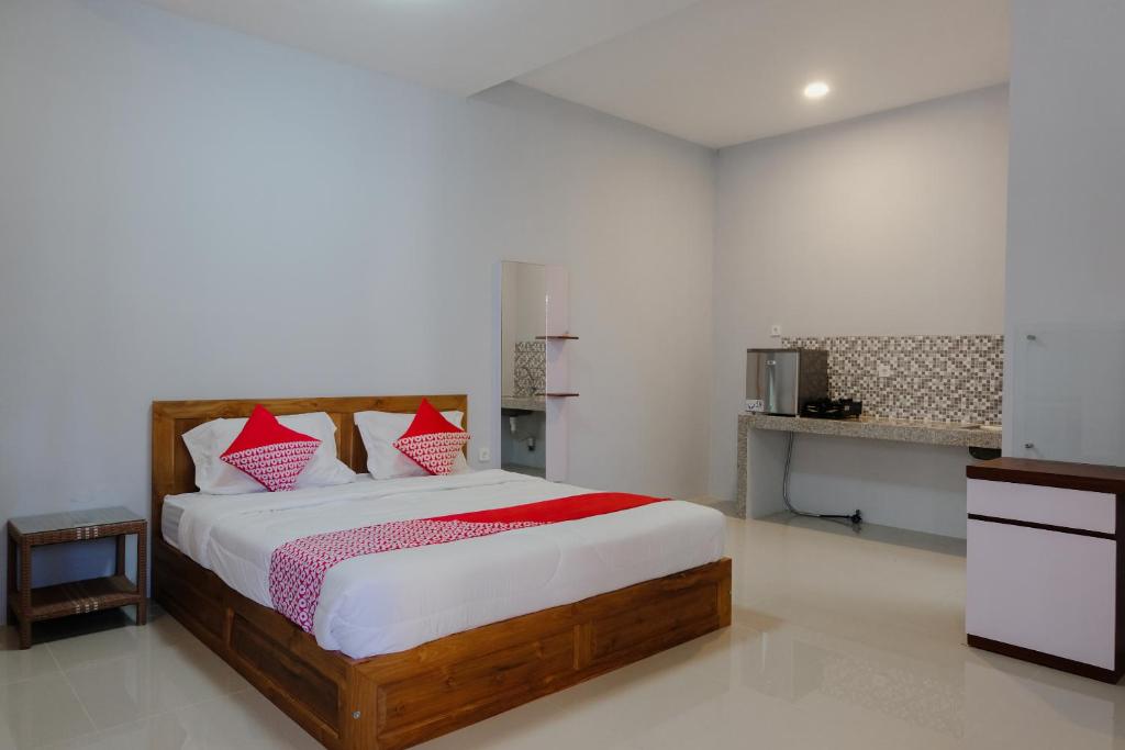 sypialnia z łóżkiem z białymi i czerwonymi poduszkami w obiekcie SUPER OYO 1579 Kate'el Inn w mieście Banyuwangi