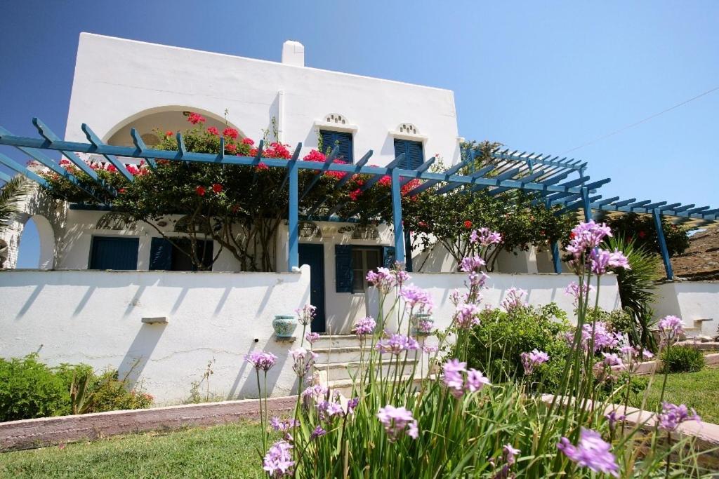 a white house with flowers in front of it at Vriokastro in Tinos