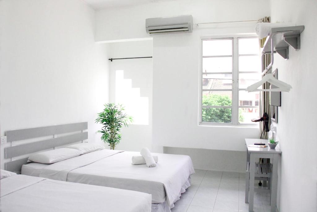 two beds in a white room with a window at 39 Guest House in Melaka