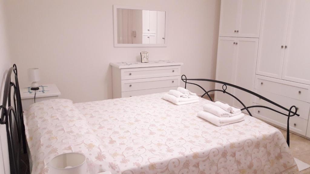 a white bedroom with a bed with two towels on it at Domuspes in Sedilo