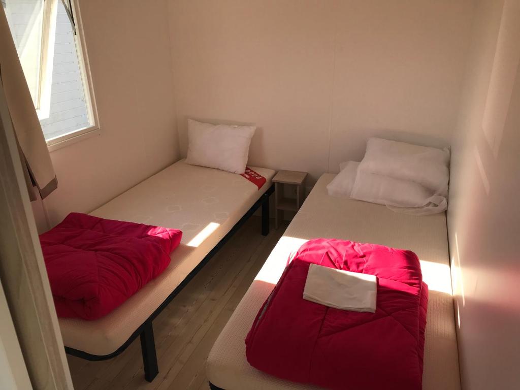 two beds in a small room with red sheets at Domaine in Litteau