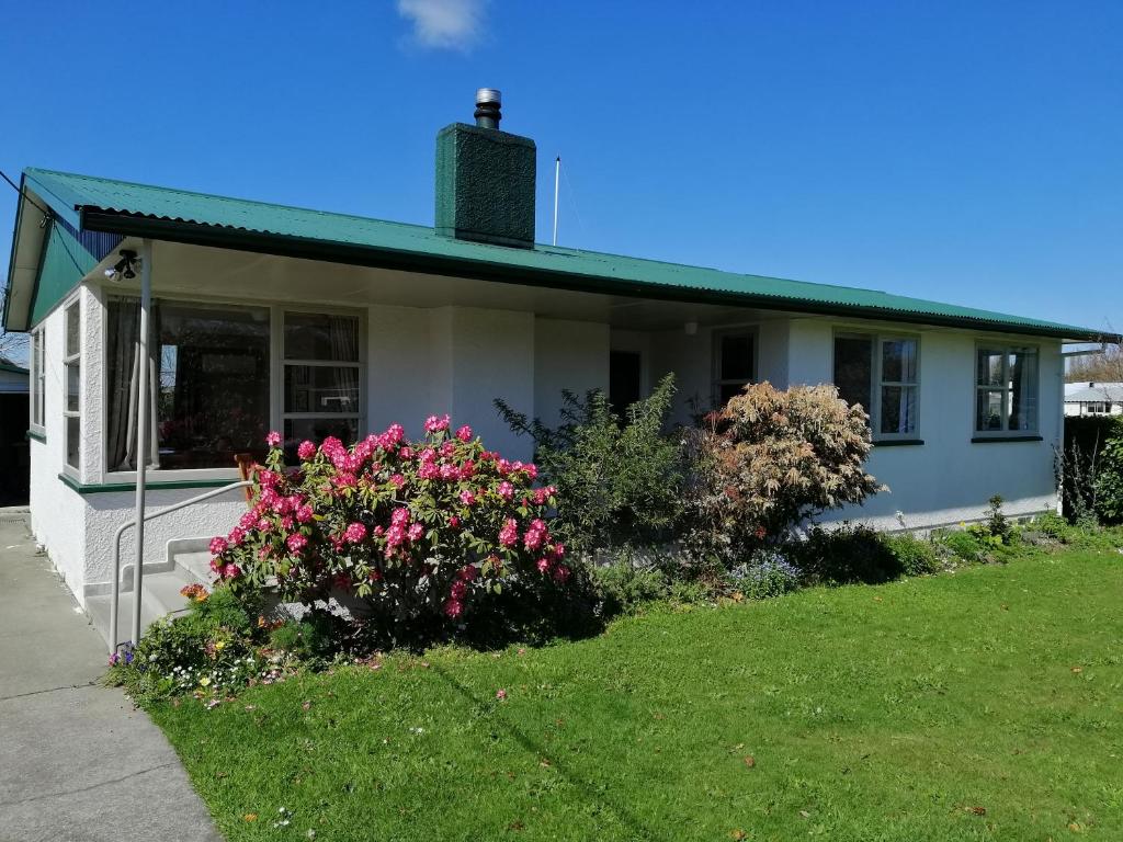 a white house with pink flowers in the yard at Super Central Cosy Greytown House with Garage in Greytown