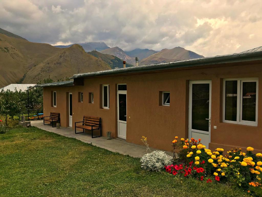 a house with benches and flowers in front of it at Piligrim Kazbegi in Kazbegi
