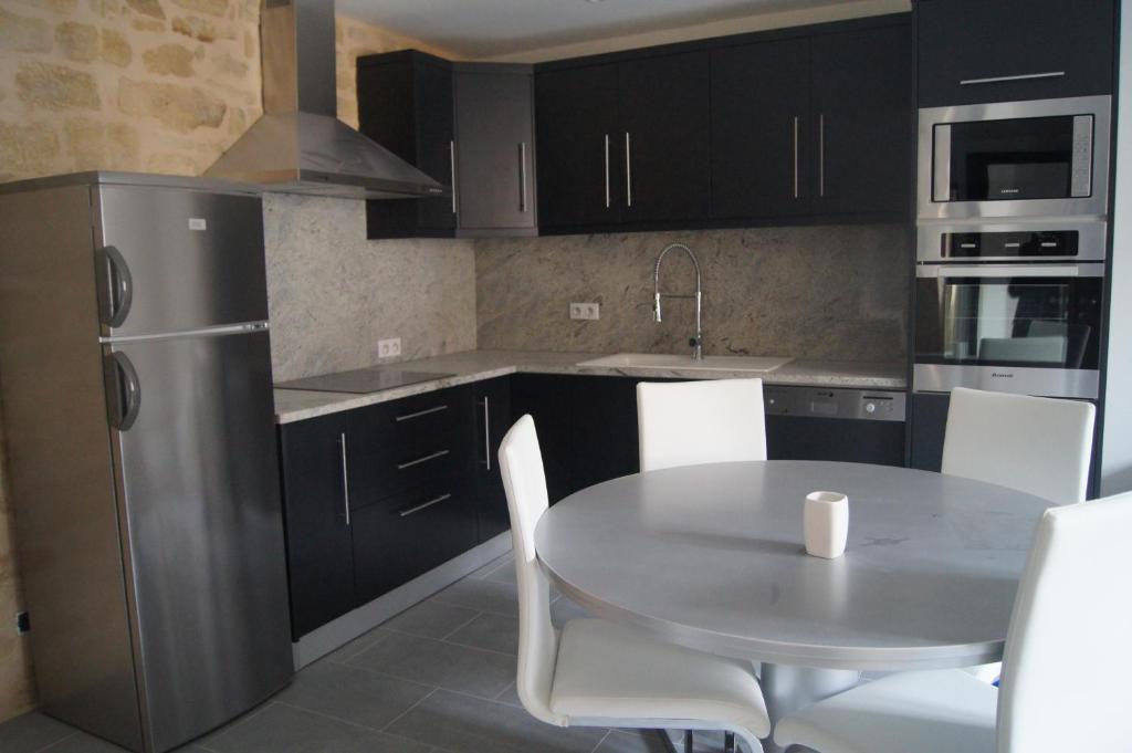 eine Küche mit einem Tisch, einer Spüle und einem Kühlschrank in der Unterkunft Les Remparts de Sarlat in Sarlat-la-Canéda