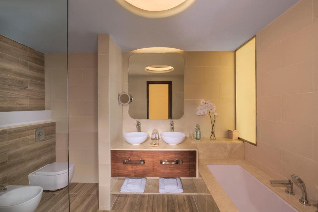 a bathroom with two sinks and a tub and a mirror at The Retreat Palm Dubai MGallery by Sofitel in Dubai