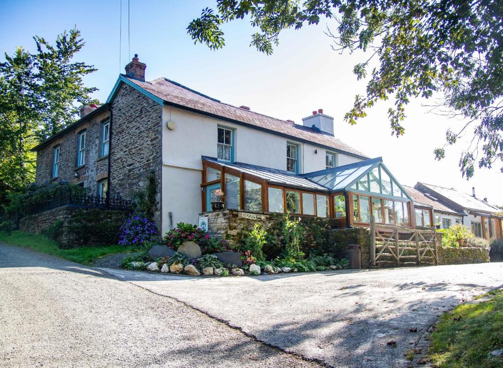 Una gran casa blanca con un salón acristalado en una calle en Penybanc Farm en Llandysul