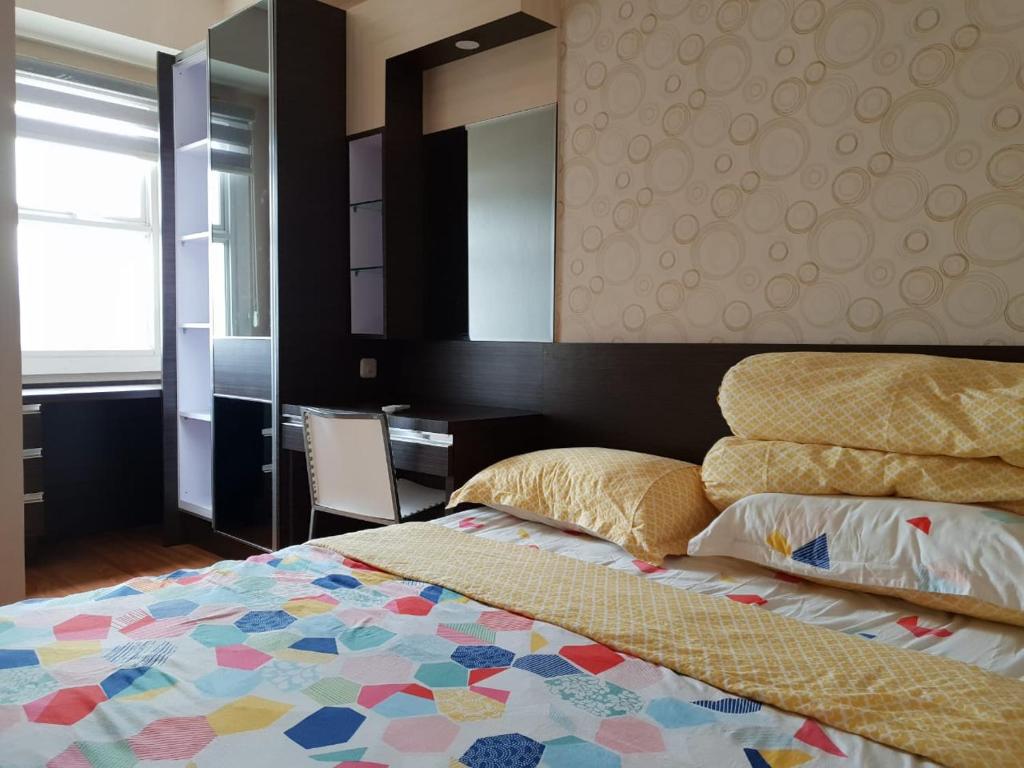 een slaapkamer met een bed, een bureau en een spiegel bij Will's Apartment - Parahyangan Residence in Bandung