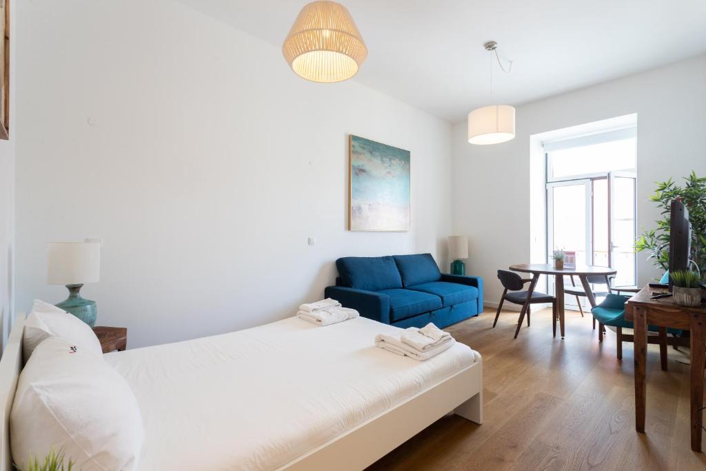 - un salon avec un lit et un canapé bleu dans l'établissement FLH Restauradores Modern Studios, à Lisbonne