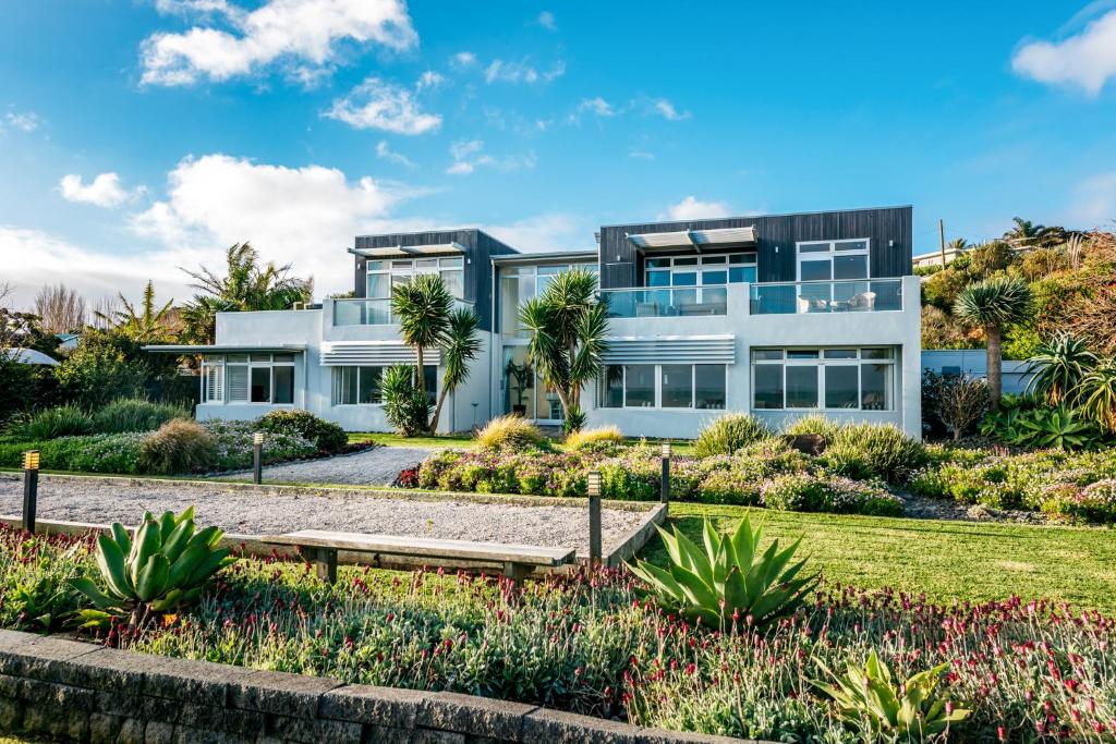 a house with a garden in front of it at Waiheke Waterfront Lodge in Oneroa