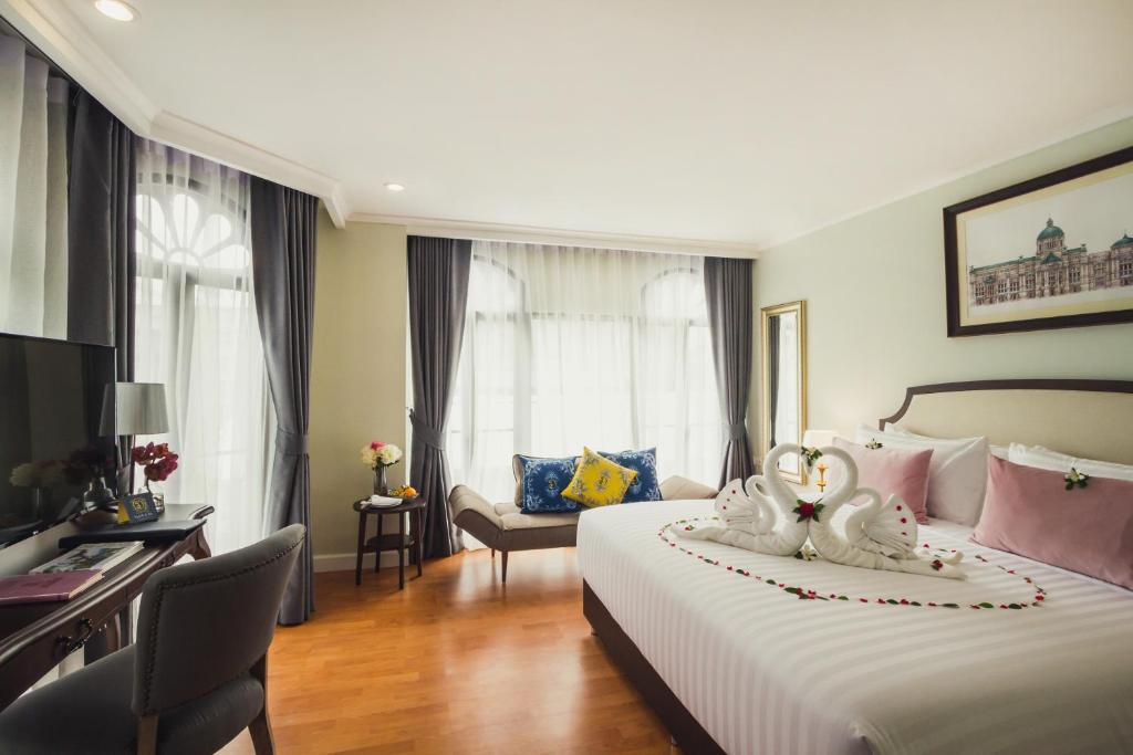 A decorated guest room with a large bed, desk and separate window-side seating.