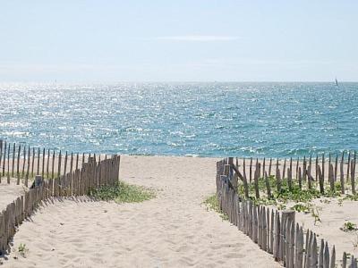 a wooden fence on a beach with the ocean at La Maison Bleue à 40m de la plage in La Turballe