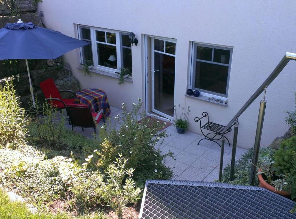 - une terrasse avec 2 chaises et un parasol dans l'établissement Ferienwohnung Schwanbergblick, à Mainbernheim