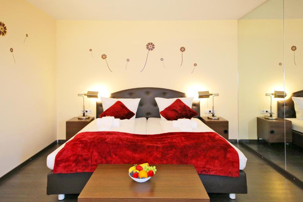 a bedroom with a red bed with a bowl of fruit on a table at Hotel Kick in Rauenberg