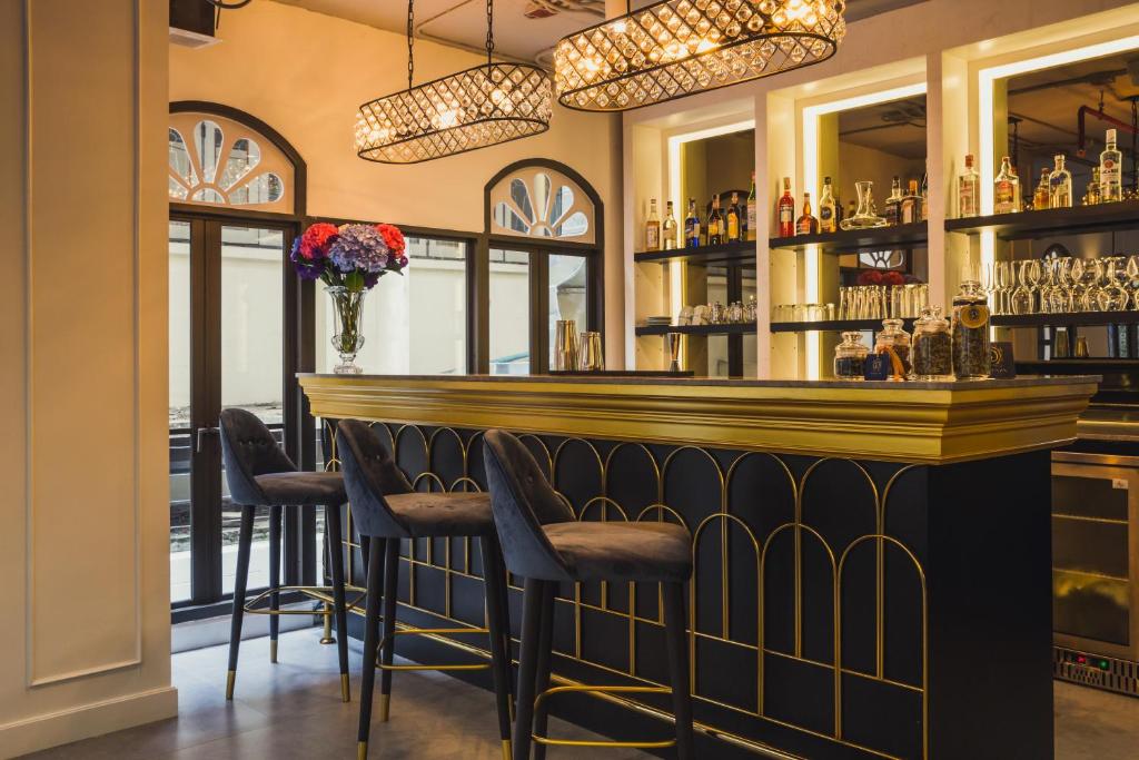 A close view of the hotel bar with upholstered stools and illuminated liquor shelves.
