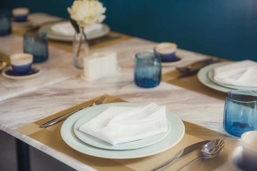 A formally set restaurant table with folded napkins, plates and blue glassware.