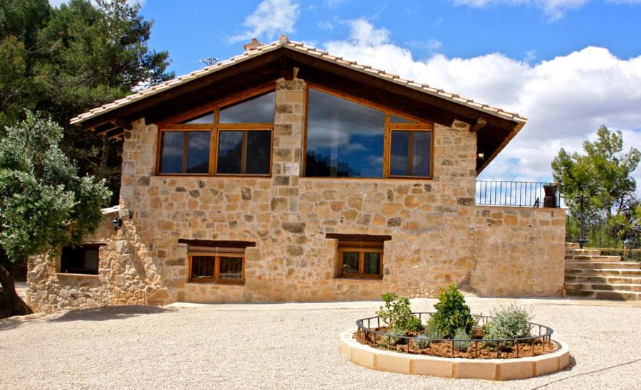 ein Steinhaus mit einem großen Fenster in der Unterkunft La Serra Rural in Horta de San Joan
