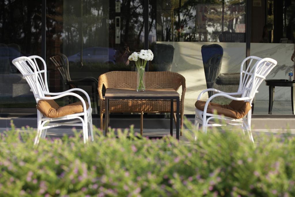 trzy białe krzesła i stół z wazonem kwiatów w obiekcie I am Jazz Hotel w mieście Johor Bahru