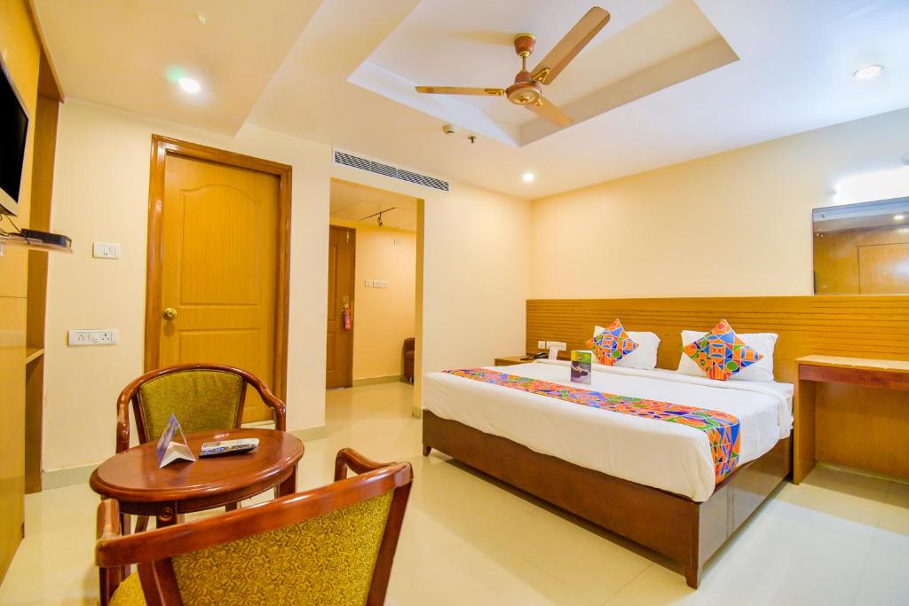 een slaapkamer met een bed, een tafel en een plafond bij FabExpress Deccan Heritage Abids in Hyderabad