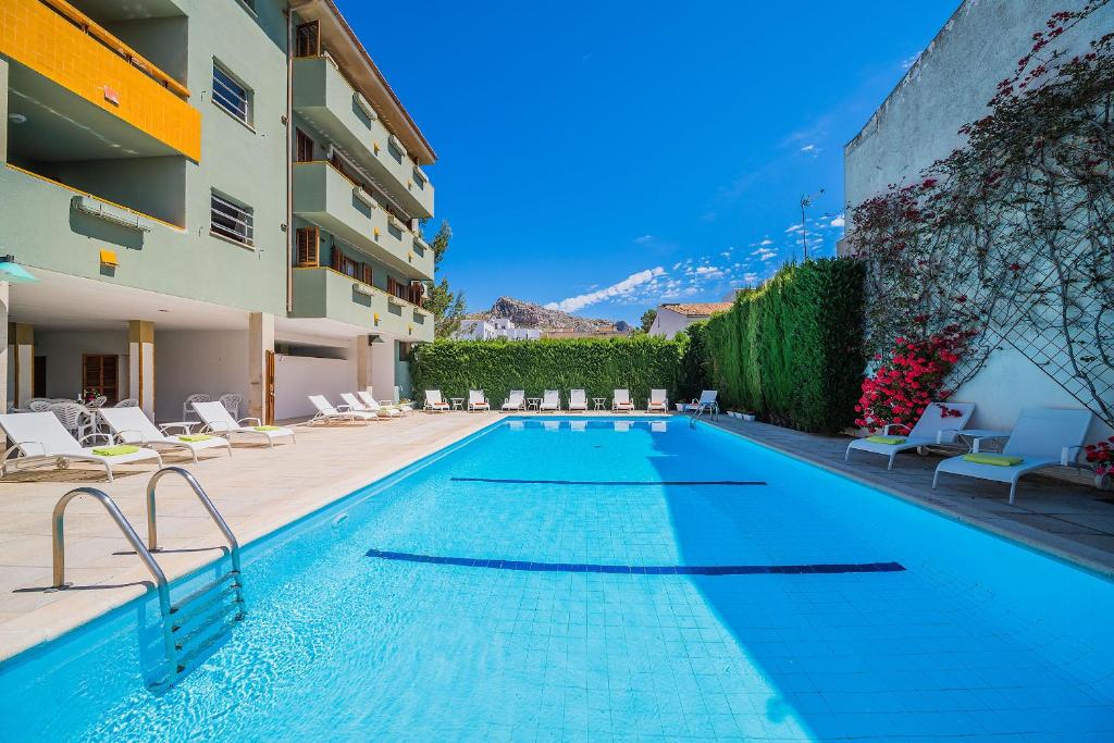 a swimming pool next to a building with chairs at Apartamento Bressol D in Port de Pollensa