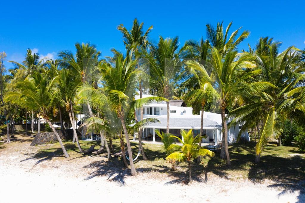 a white house on the beach with palm trees at Villa Eva in Belle Mare