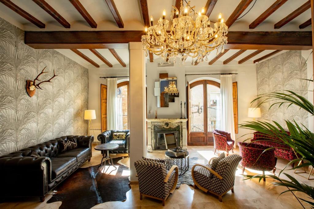 uma sala de estar com um sofá e cadeiras e um lustre em El Palauet del Priorat em Cornudella