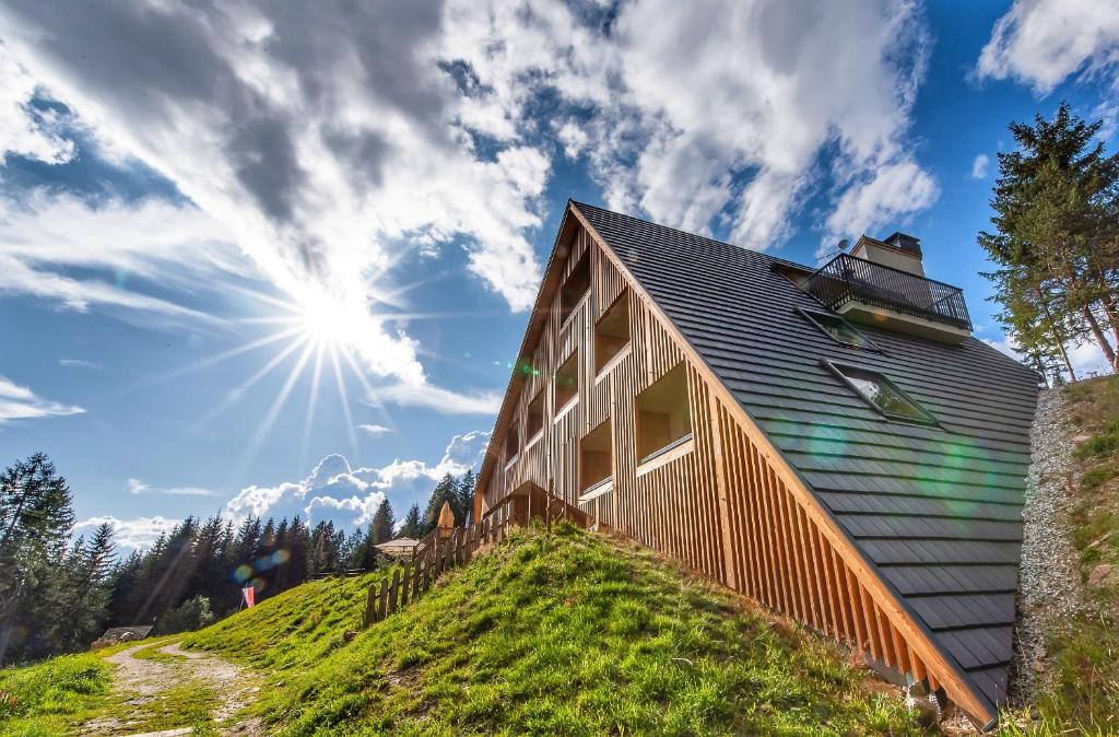 Oberhauser Hütte Rodenecker - Lüsner Alm في لوسون: منزل على تلة مع الشمس في السماء