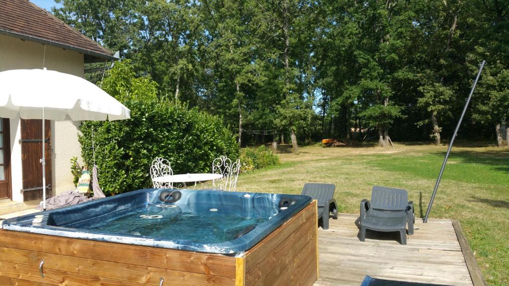 a hot tub with two chairs and an umbrella at Bienvenue en Périgord in Cendrieux