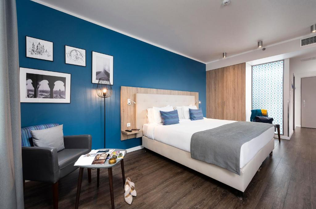 a bedroom with a large bed and a chair at Three Corners Lifestyle Hotel in Budapest