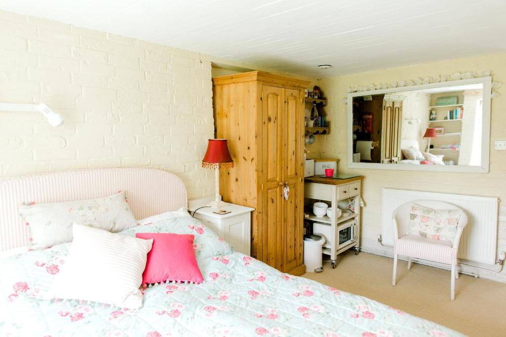 1 dormitorio con 1 cama con almohadas rosas y blancas en Cosy Cottage ground floor bedroom ensuite with private entrance, en Chichester