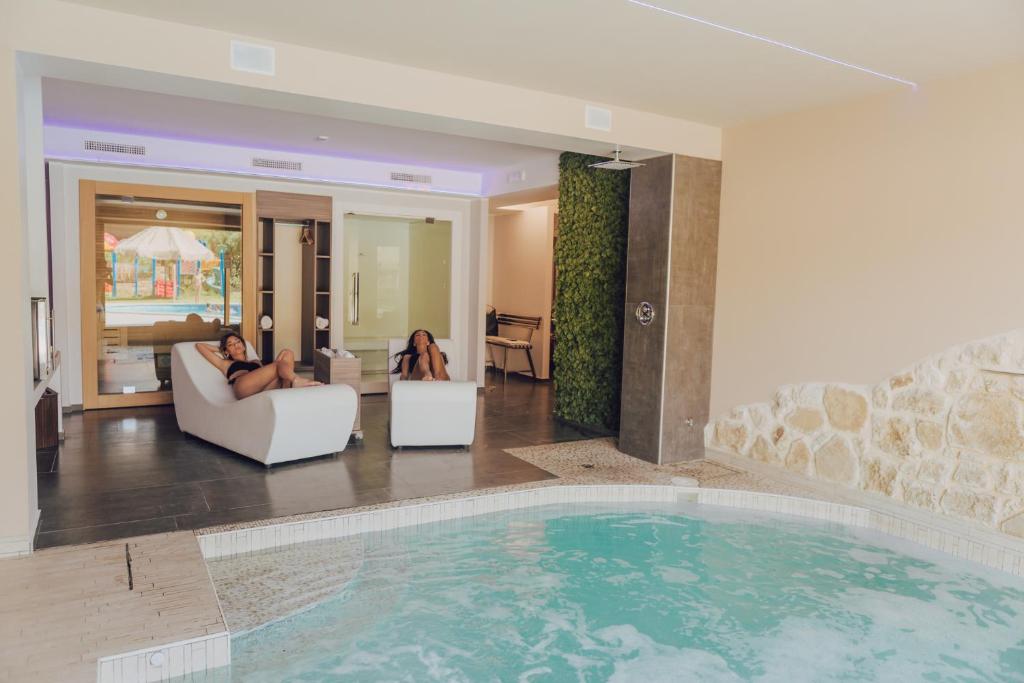 two people sitting on chairs in a living room with a pool at Halanus Hotel And Resort in Alanno