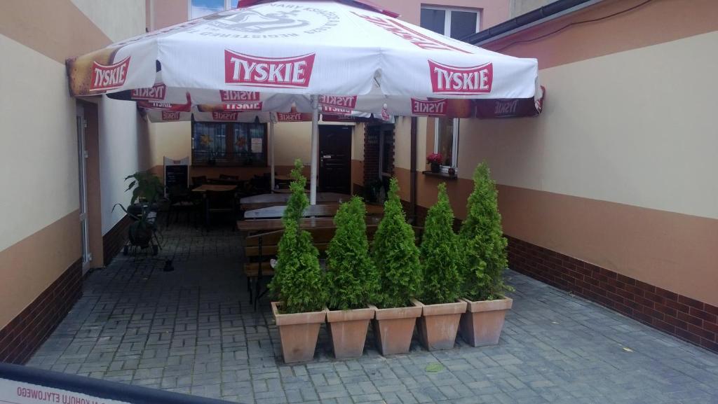 un restaurant avec un parasol et des plantes devant lui dans l'établissement Apartamenty NOCLEGI BĘDZIN, à Będzin