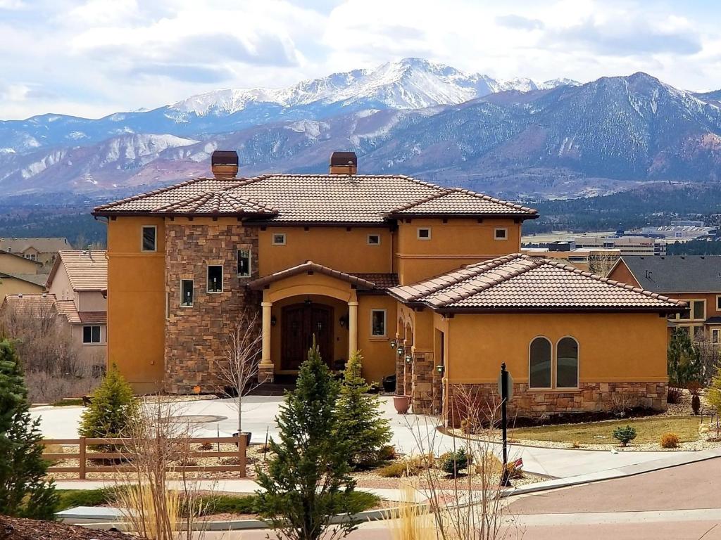 ein großes gelbes Haus mit Bergen im Hintergrund in der Unterkunft Chateau du Pikes Peak, a Tuscany Retreat in Colorado Springs