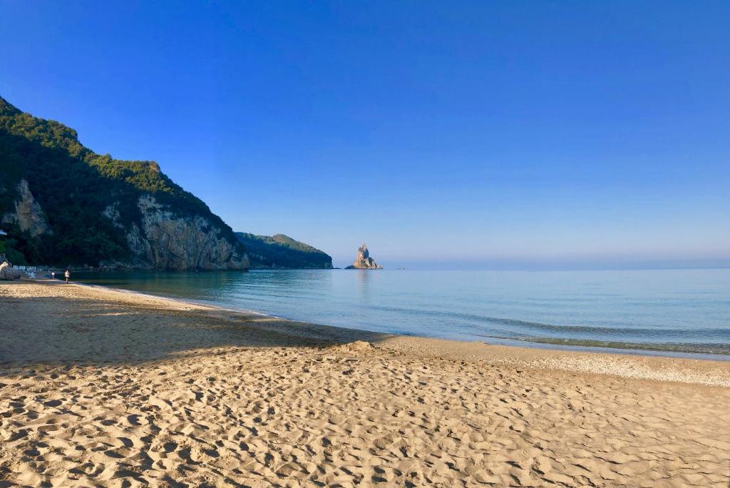 einen Sandstrand mit einem Felsen im Wasser in der Unterkunft Sebastian's - Agios Gordios Beach in Agios Gordios