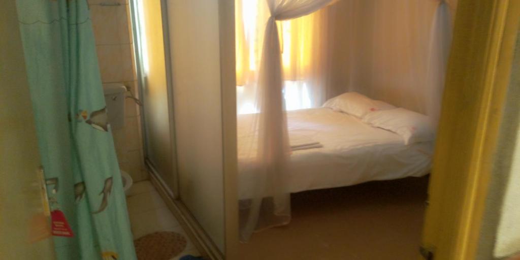 a small bedroom with a bed and a window at Hotel Jaffers Nairobi in Nairobi