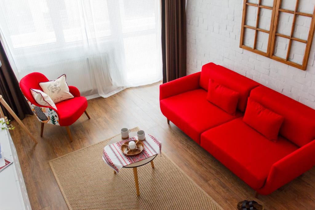 a living room with a red couch and two chairs at Grand Accommodation Apartments in Bucharest
