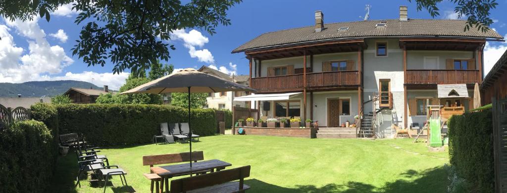 ein Haus mit einem Garten mit Stühlen und einem Sonnenschirm in der Unterkunft Platzerhof in Welsberg-Taisten