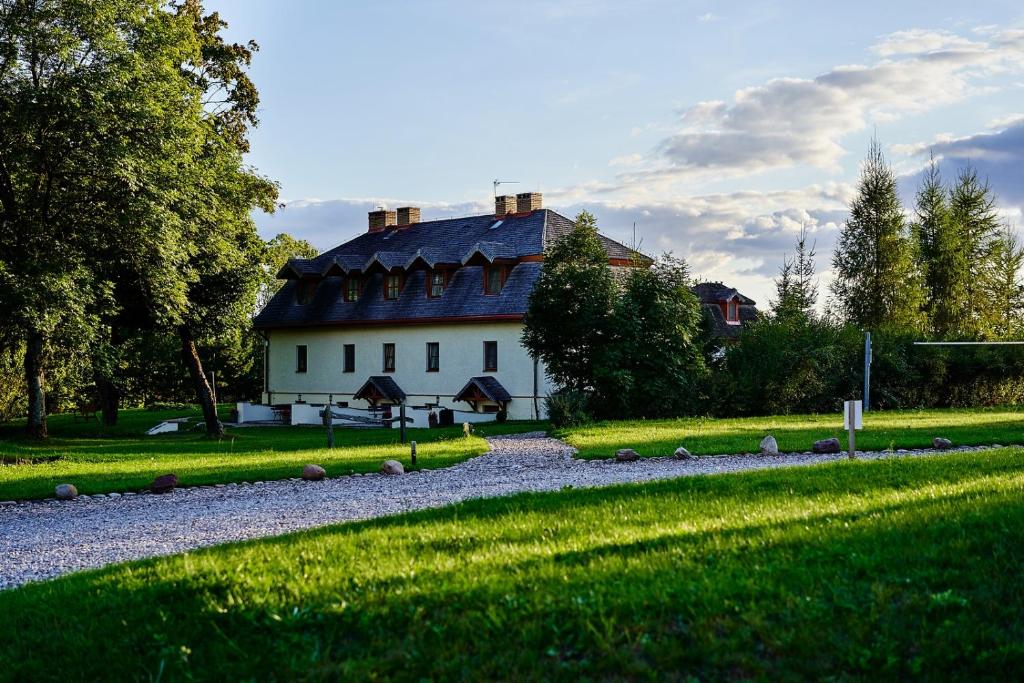 ein großes weißes Haus mit schwarzem Dach in der Unterkunft Folwark Hutta in Suwałki