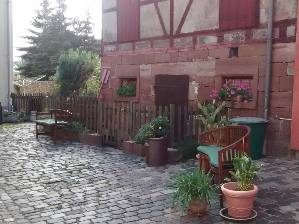 a patio with benches and potted plants and a fence at Landhauspension Rank in Bad Berka