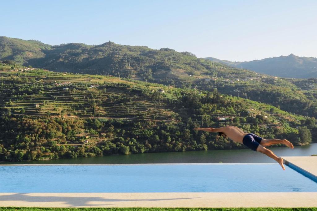 una persona saltando de un trampolín a un lago en Casa da Mouta - Douro Valley, en Baião