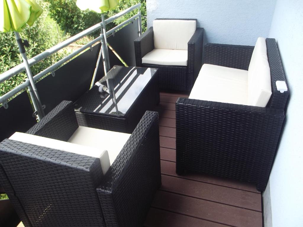 four wicker chairs and tables on a balcony at Ferienwohnung in Puschendorf in Puschendorf