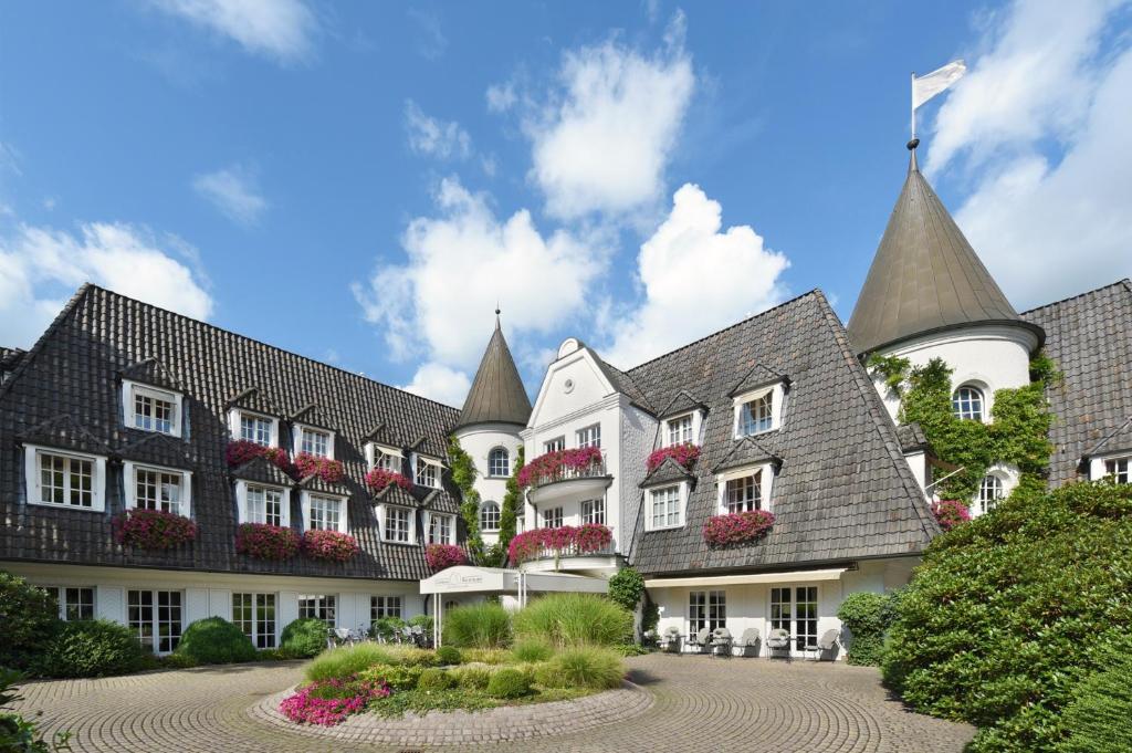 ein großes weißes Gebäude mit schwarzem Dach in der Unterkunft Hotel Landhaus Wachtelhof in Rotenburg an der Wümme