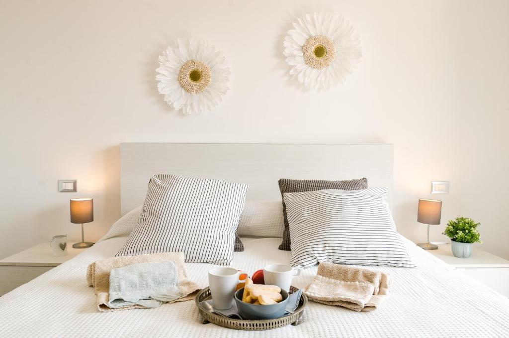 Una cama blanca con una bandeja de comida. en FCO Luxury Apartments, en Fiumicino