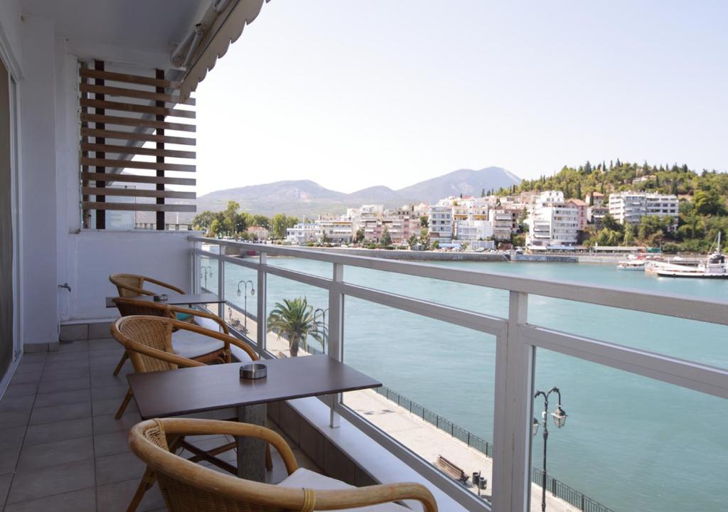 a balcony with tables and chairs and a view of the water at Chalkida Seafront Apartment in Chalkida
