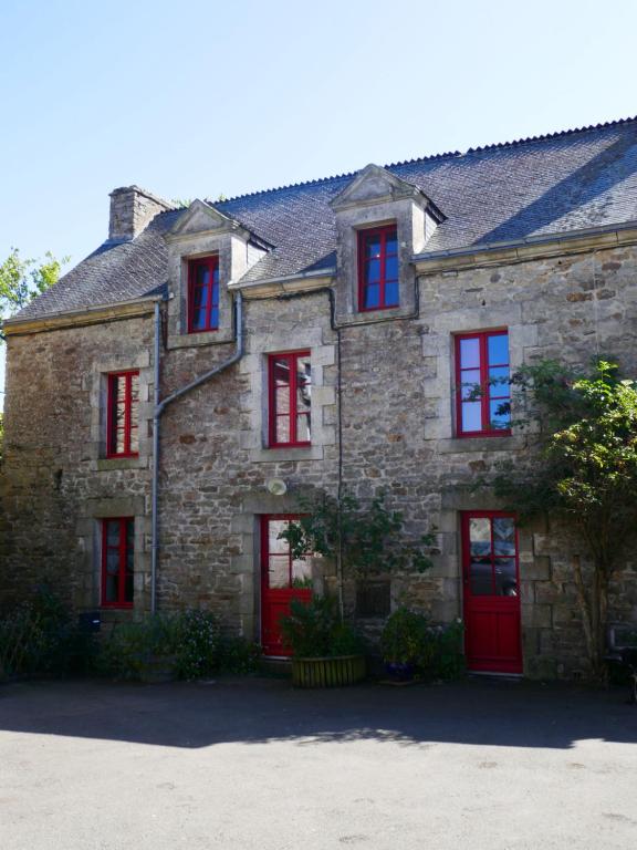 une ancienne maison en pierre avec des portes rouges dans l'établissement Maison familiale, 15couchages, de charme au cœur de la Bretagne - 20 min de Vannes, à Lizio